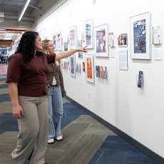 Two students exploring the "Creating Community Through Books" exhibition in UCSB Library.