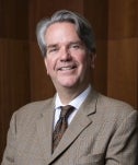 Alan Grosenheider posed in front of a panel wooden wall